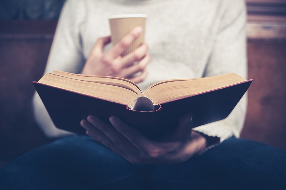 Young,man,is,sitting,on,a,sofa,and,reading,a